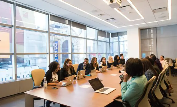 Diverse group of people sitting around a board room table with an urban environment outside