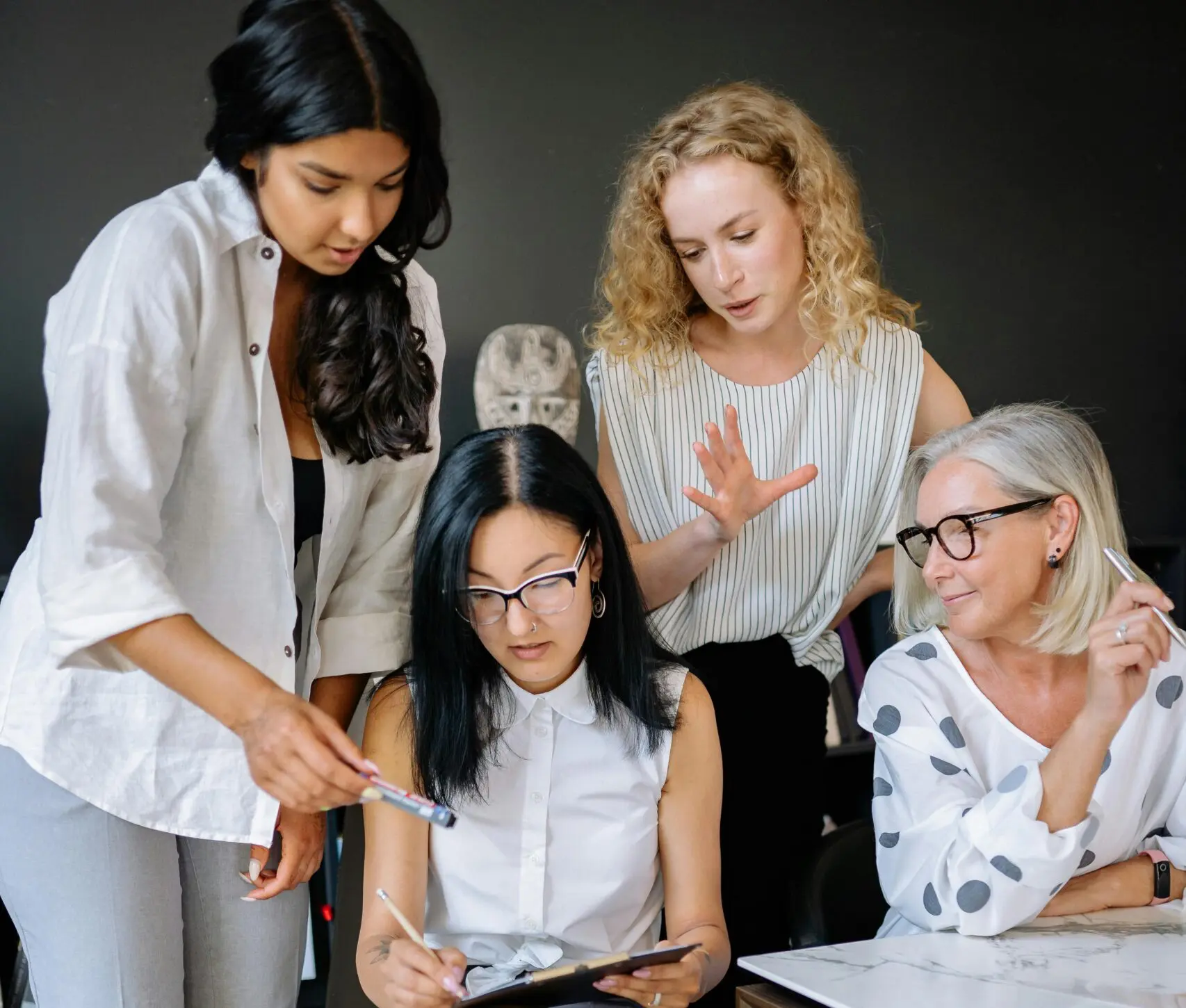 Group of female office workers looking through documents together.